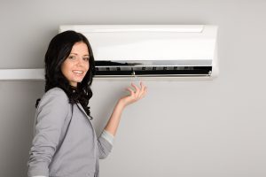 Beautiful smiling girl showing the air conditioner